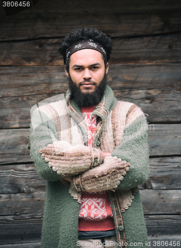 Image of portrait of young hipster in front of wooden house