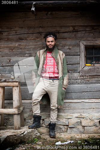 Image of portrait of young hipster in front of wooden house