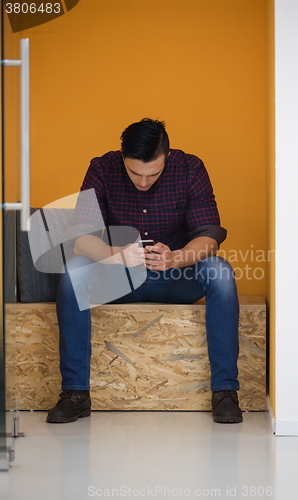 Image of man in crative box working on smart phone