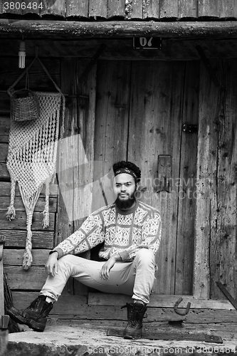 Image of portrait of young hipster in front of wooden house