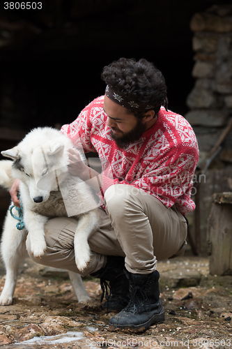 Image of hipster with dog in front of wooden house