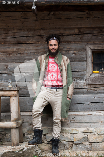 Image of portrait of young hipster in front of wooden house