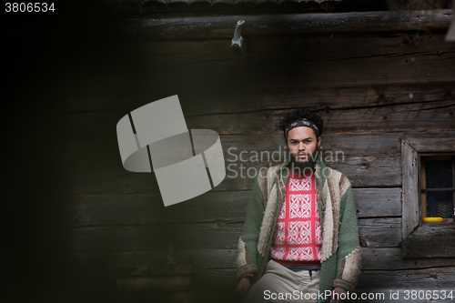 Image of portrait of young hipster in front of wooden house