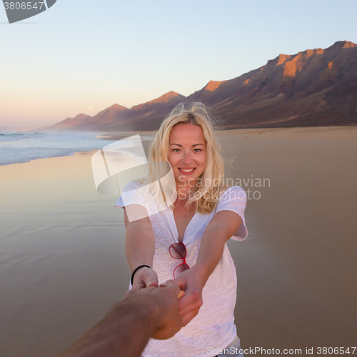 Image of Romantic couple, holding hands, having fun on beach.