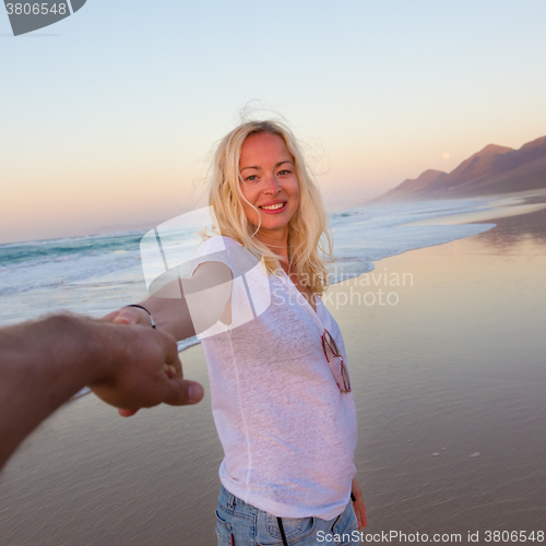 Image of Romantic couple, holding hands, having fun on beach.