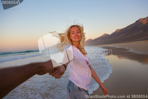 Image of Romantic couple, holding hands, having fun on beach.