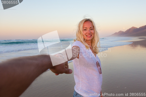 Image of Romantic couple, holding hands, having fun on beach.