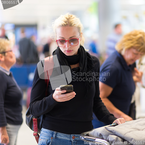 Image of Female traveler using cell phone while waiting.