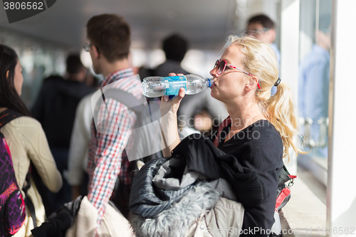 Image of  Woman drinking water while queuing to board plane.