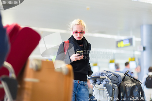 Image of Female traveler using cell phone while waiting.