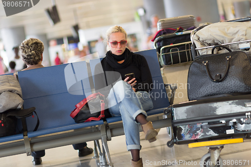 Image of Female traveler using cell phone while waiting.