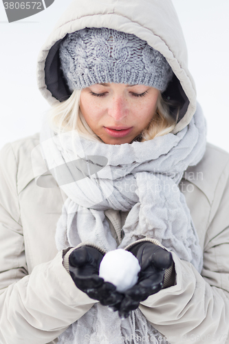 Image of Girl  holding snowball in cold winter time.