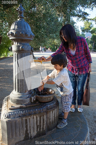 Image of boy with his mother washing his hands under water stream from hy