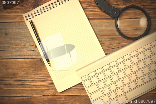 Image of still life with note pad, computer keyboard, magnifying glass an