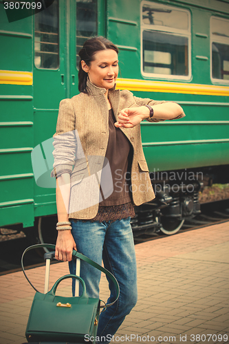 Image of beautiful woman looks at his watch on the platform of the railwa