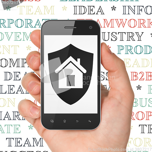 Image of Business concept: Hand Holding Smartphone with Shield on display