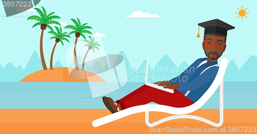 Image of Graduate lying on chaise lounge with laptop.