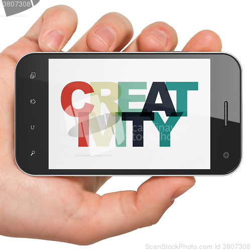Image of Marketing concept: Hand Holding Smartphone with Creativity on  display