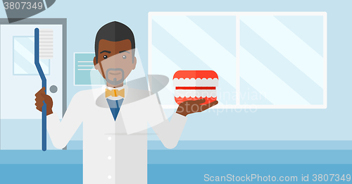 Image of Dentist with dental jaw model and toothbrush.