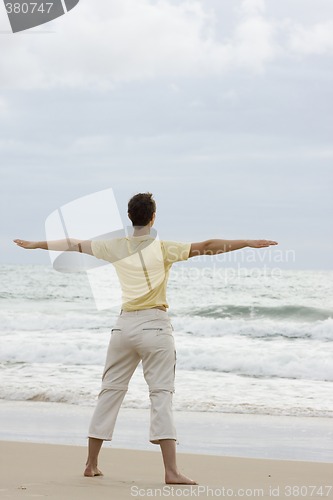 Image of Woman doing yoga on beach