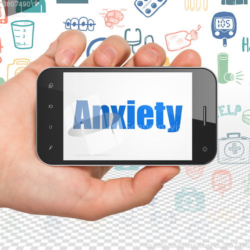 Image of Healthcare concept: Hand Holding Smartphone with Anxiety on display