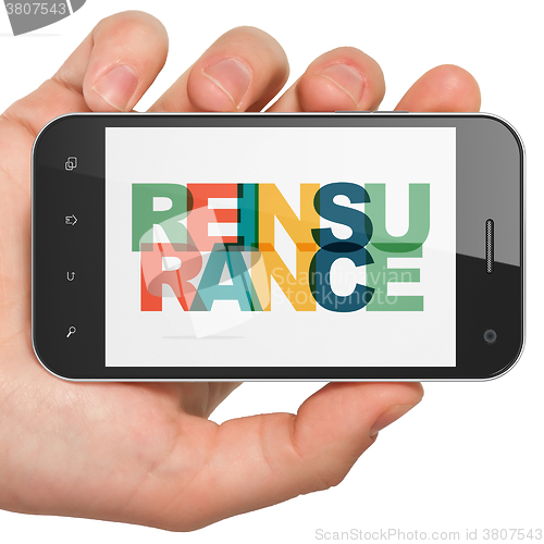 Image of Insurance concept: Hand Holding Smartphone with Reinsurance on  display