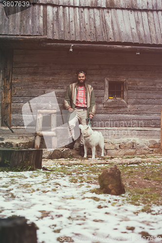 Image of hipster with dog in front of wooden house