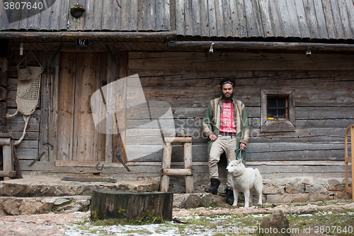 Image of hipster with dog in front of wooden house