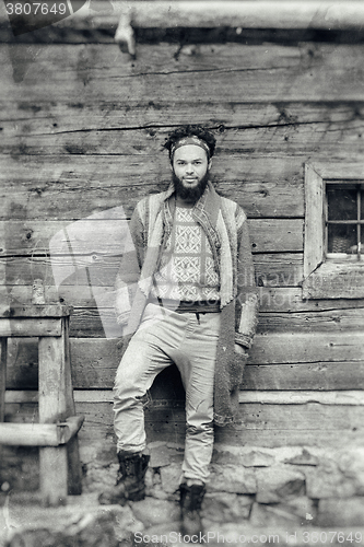 Image of portrait of young hipster in front of wooden house