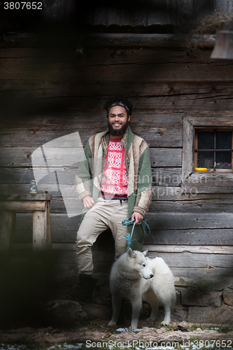 Image of hipster with dog in front of wooden house