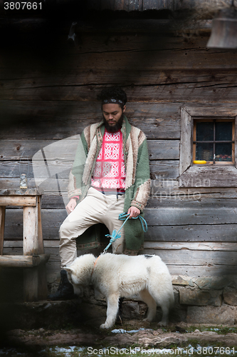 Image of hipster with dog in front of wooden house