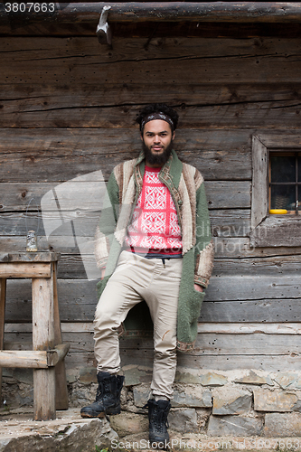 Image of portrait of young hipster in front of wooden house