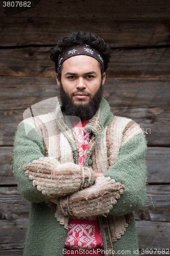 Image of portrait of young hipster in front of wooden house