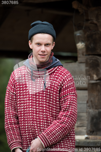 Image of young hipster in front of wooden house