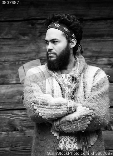 Image of portrait of young hipster in front of wooden house