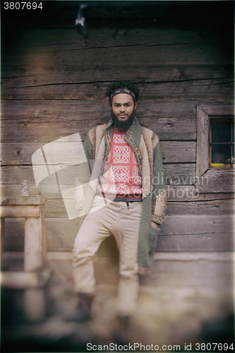 Image of portrait of young hipster in front of wooden house