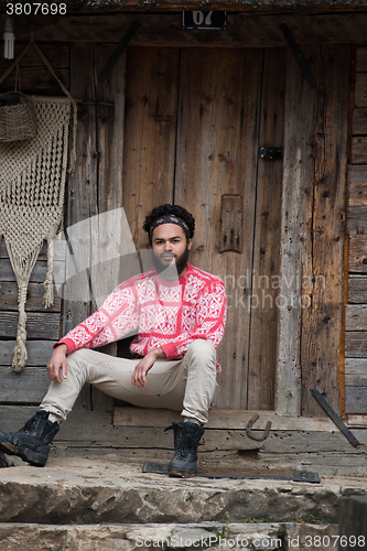 Image of portrait of young hipster in front of wooden house