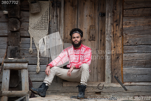 Image of portrait of young hipster in front of wooden house