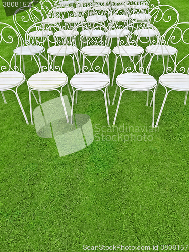 Image of Green lawn with empty white chairs