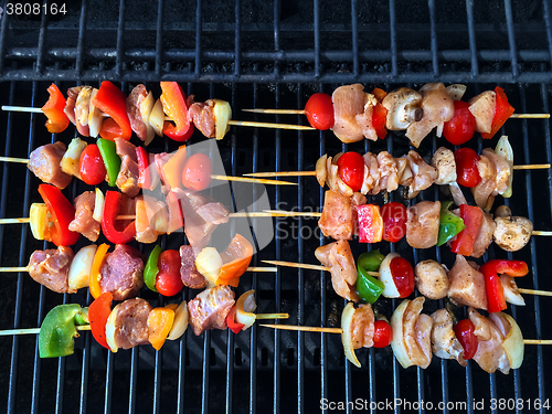 Image of Barbecue grill with meat and vegetable skewers