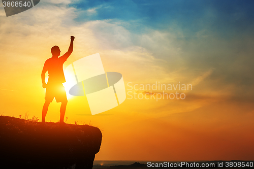 Image of Man stands near the cross on top of mountain