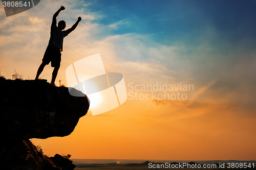 Image of Man stands near the cross on top of mountain