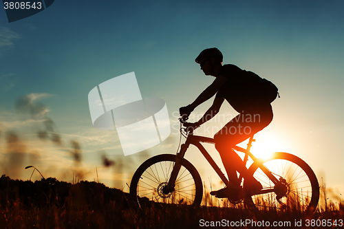 Image of Man Cyclist with bike on sunset