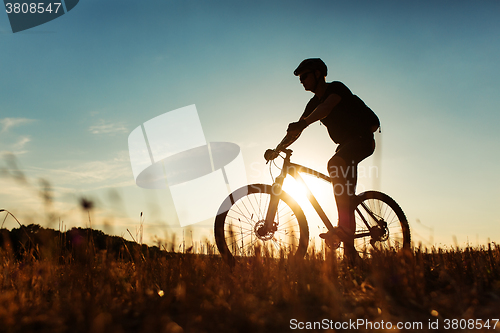 Image of Man Cyclist with bike on sunset