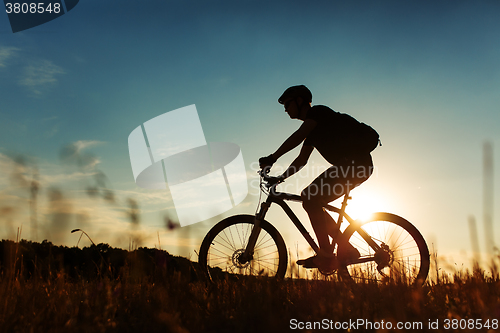 Image of Man Cyclist with bike on sunset