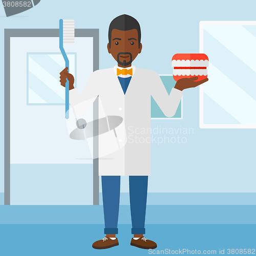 Image of Dentist with dental jaw model and toothbrush.