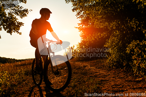 Image of Man Cyclist with bike on sunset