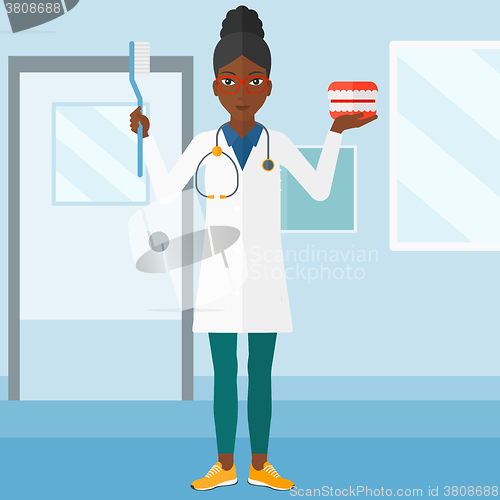 Image of Dentist with dental jaw model and toothbrush.