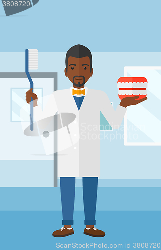 Image of Dentist with dental jaw model and toothbrush.
