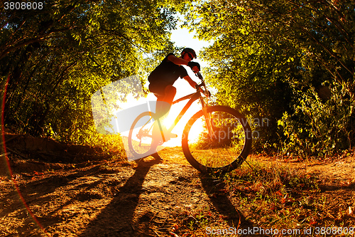 Image of Man Cyclist with bike on sunset